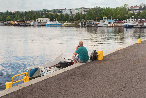 Egy magányos férfi telefonál egy mólón ülve a finnországi Jyvaskylában.. - Fotó, kép