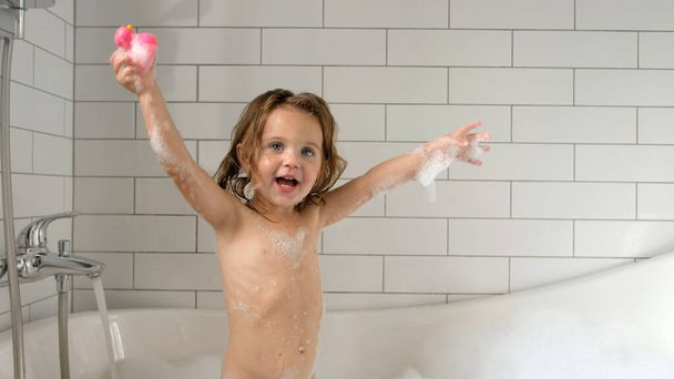 Charming child playing with foam and toy in bath tube - Photo, image