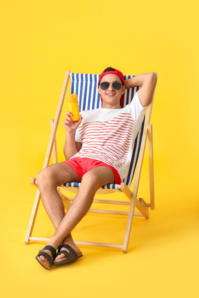 Happy young man with sun protection cream on color background - Foto, Imagem