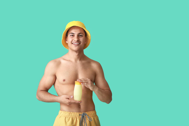 gelukkig jongeman met zon bescherming crème op kleur achtergrond - Foto, afbeelding