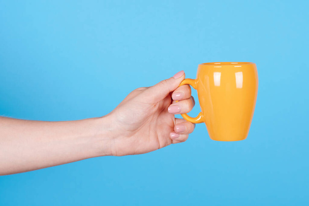 Hand with yellow coffee mug. - Zdjęcie, obraz