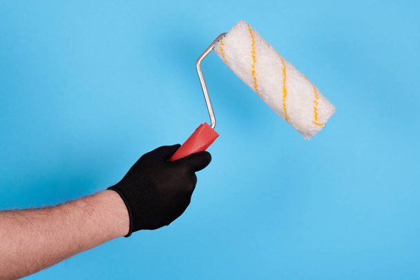 Hand in working glove with paint roller. - Photo, Image