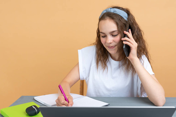 Focused teenage girl holding pen and using laptop while studying at home - Valokuva, kuva
