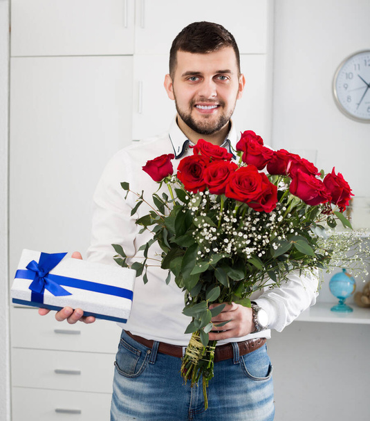 Smiling young male ready with bouquet and gift for romantic dinner  - Foto, afbeelding