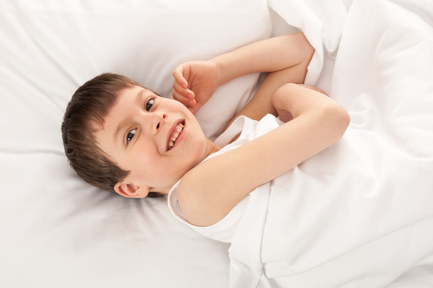 cheerful boy in white bed - Foto, afbeelding
