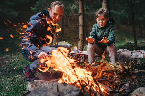 Father with son makes campfire in forest - Foto, Imagen