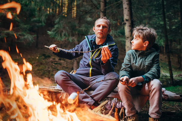 Picnic in forest - father and son roste marshmallow on campfire - Foto, Bild