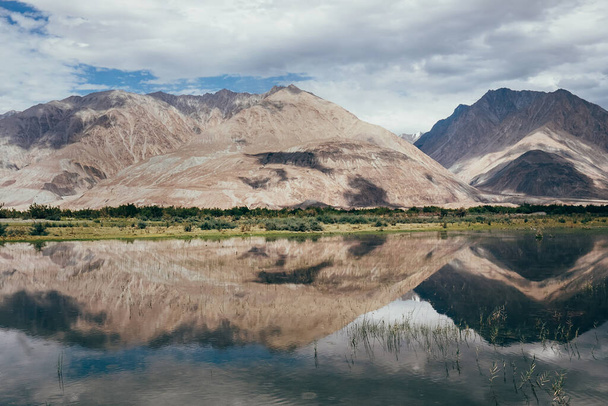Mountain peaks reflect in water Nubra river - Фото, изображение