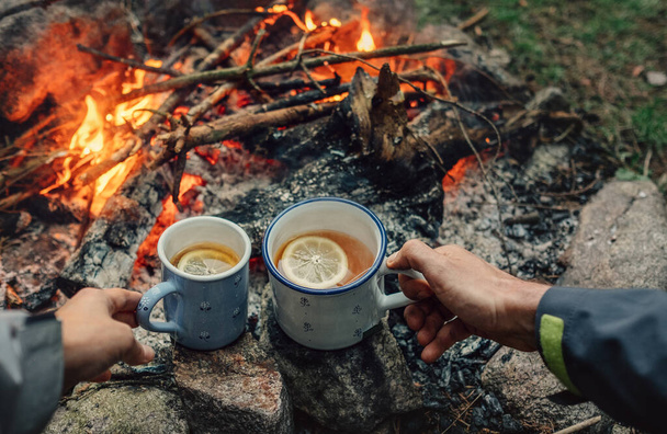 Tea party near campfire. Couple drink tea with lemon - Foto, Imagen