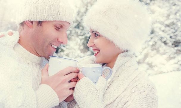 Cozy dressed couple drink hot tea on snow forest glade - Fotoğraf, Görsel