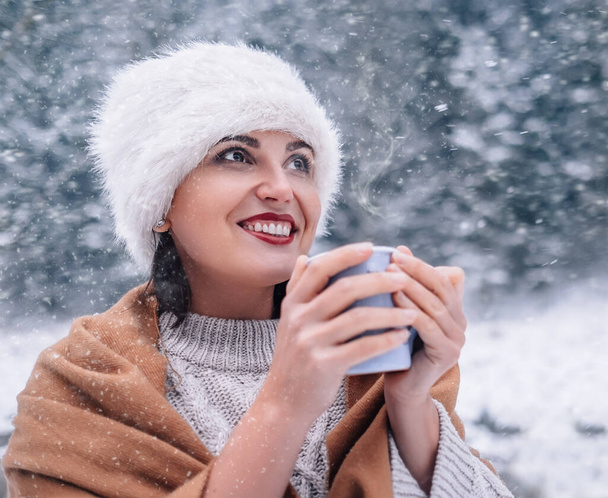 Cheerful woman with cup of hot tea in winter forest - Fotografie, Obrázek