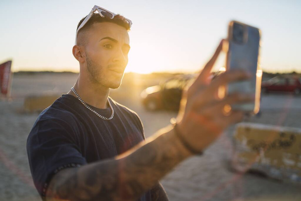 A vertical shot of a Caucasian male with tattoos taking a selfie with his smartphone - Foto, Imagem