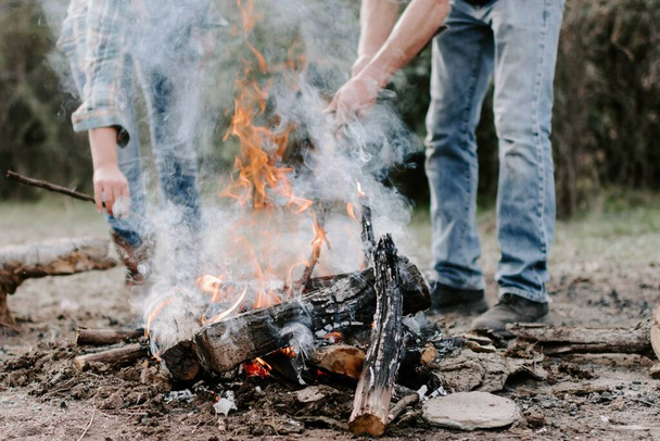 A closeup of people making a bonfire in the forest - Fotó, kép