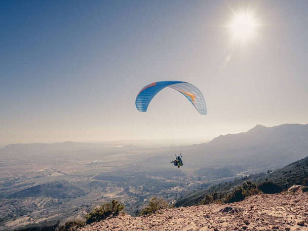 A person paragliding above the mountains under the sunlight at daytime - Foto, Bild