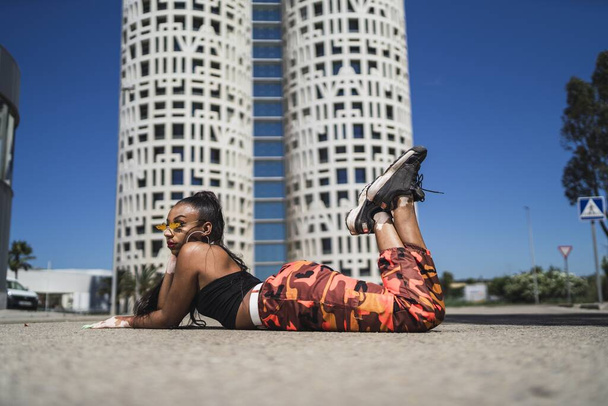 A sexy African American female posing on the asphalt in front of a modern building - Foto, Imagem
