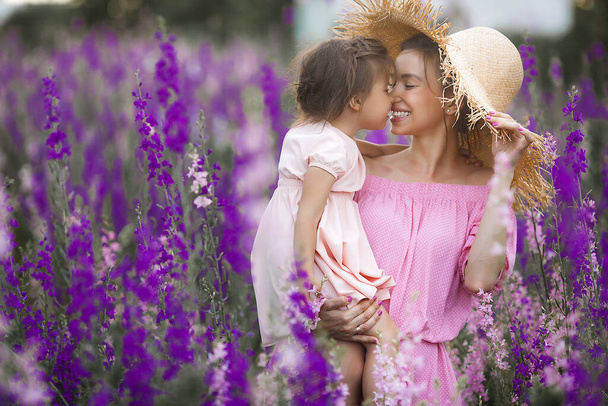 Mooi klein meisje en haar moeder met bloemen. Familie buiten - Foto, afbeelding