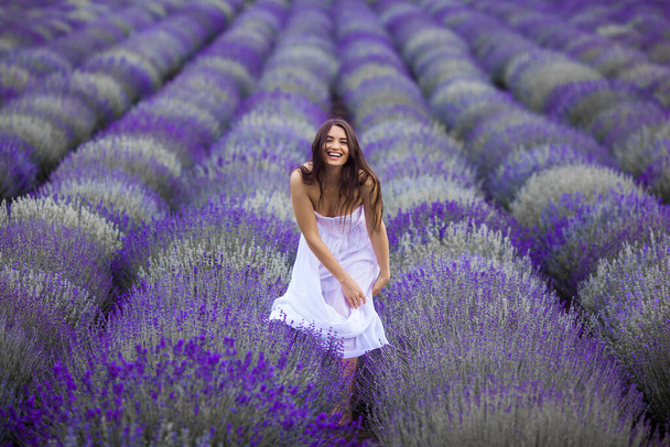 Jonge vrouw in het lavendelveld. Mooie vrouw op zomer bloemen achtergrond - Foto, afbeelding