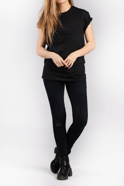 A young female wearing black short sleeve t-shirt standing against a white wall - Zdjęcie, obraz