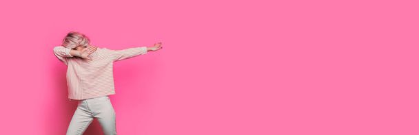 Caucasian blonde woman dabbing on a pink studio wall with empty space - Zdjęcie, obraz