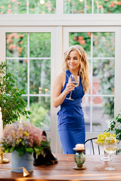 girl in blue dress standing with glass of wine. - Foto, Imagen