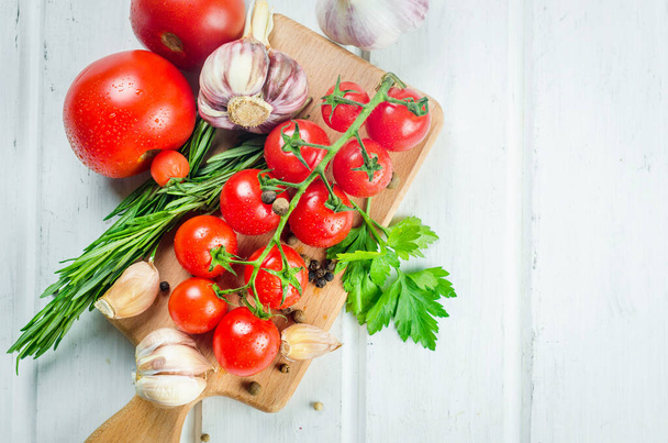 Bunch of juicy organic red cherry tomatoes with green  rosemary,  garlic and spices on white old table. Ingredients for cooking. Clean eating concept. Vegetarian diet. space for text - Fotoğraf, Görsel
