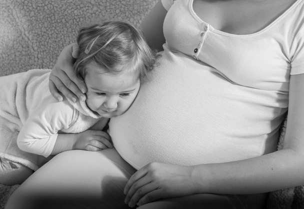 Happy child leaned her head on belly pregnant woman. - Φωτογραφία, εικόνα