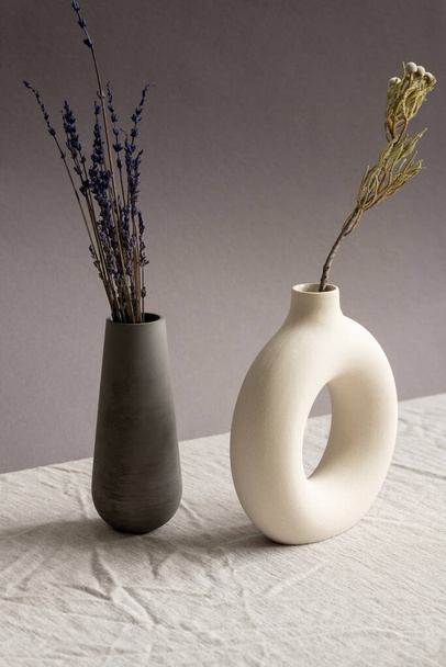 Zátiší kompozice se dvěma keramickými ručně vyrobenými vázami se sušenou levandulí a divokými květy stojící na stole potaženém bílým plátnem - Fotografie, Obrázek