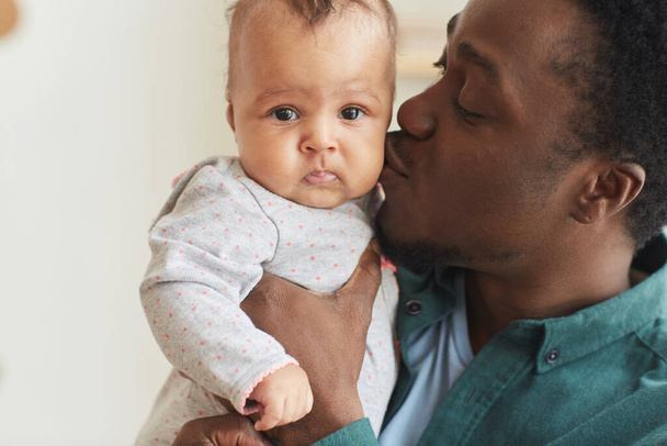 Close up portrait of happy African-American man kissing cute baby boy while holding him, copy space - Photo, Image
