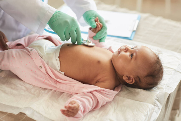 Κοντινό πλάνο του αγνώριστο γιατρό εξέταση χαριτωμένο μωρό μικτή φυλή που βρίσκεται στην αλλαγή του τραπεζιού στην κλινική, αντίγραφο χώρο - Φωτογραφία, εικόνα
