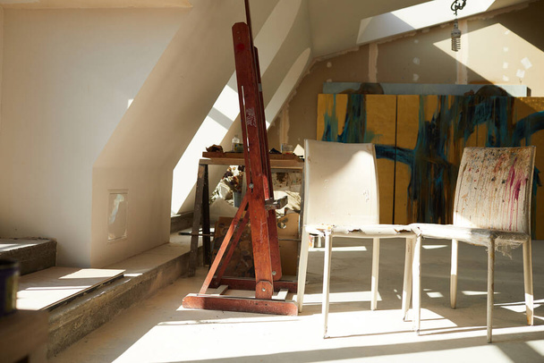 Background image of empty art studio in attic space, old chairs splattered with paint in foreground, copy space - Photo, Image