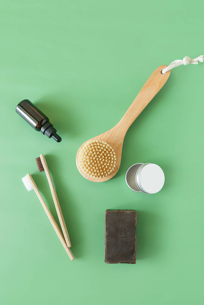 cepillos de dientes ecológicos y cepillos para el cuerpo con jabón y toalla sobre fondo verde cero residuos
 - Foto, Imagen