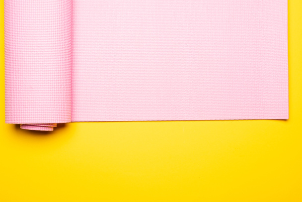 top view of pink fitness mat on yellow background - Foto, Imagem
