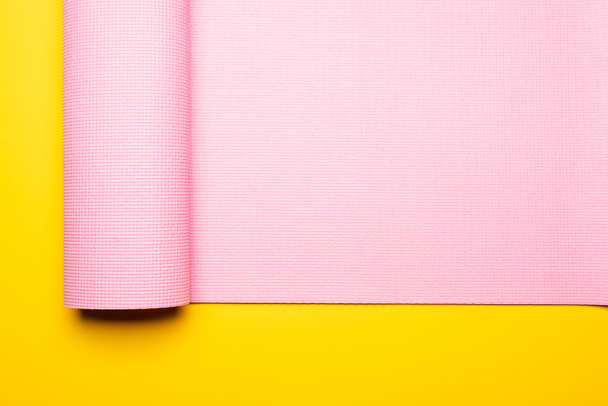 top view of pink fitness mat on yellow background - Fotó, kép