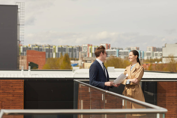 Широкий угол обзора на двух успешных бизнесменов в чате стоя на крыше современного офисного здания, копировальное пространство - Фото, изображение