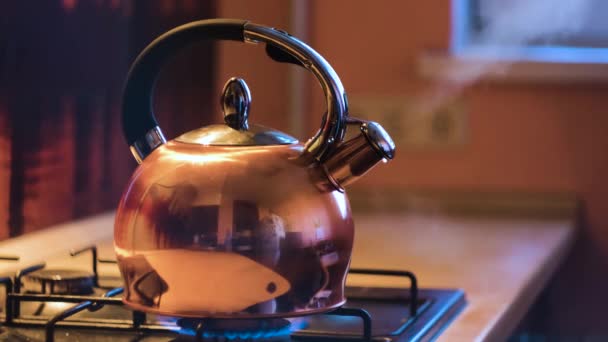 Zbliżenie czajniczek srebrny wrzący na piec. Koncepcja. Wrzący czajnik na kuchence w pięknym, wieczornym wnętrzu kuchni. Strumień pary wychodzi z czajnika na kuchence - Materiał filmowy, wideo