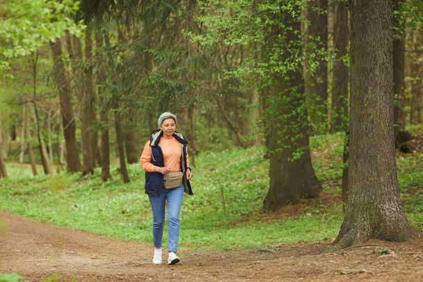 Wide angle portrait of active senior woman running during hike in beautiful autumn forest, copy space - Foto, Imagen