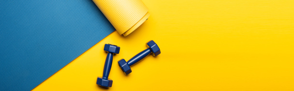 top view of blue fitness mat with dumbbells on yellow background, panoramic shot - Photo, Image