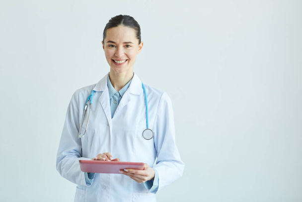 Портрет усміхненої жінки-лікаря, який тримає кишеню і дивиться на камеру, стоячи на білій стіні в клініці, копіювати простір
 - Фото, зображення