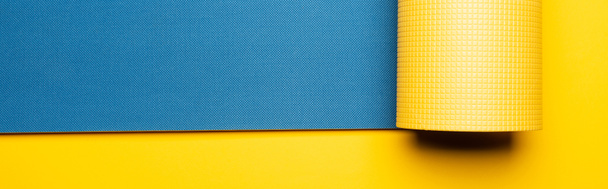 vista superior de la estera de fitness azul sobre fondo amarillo, plano panorámico
 - Foto, Imagen