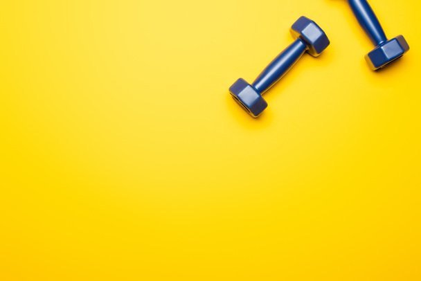 top view of blue dumbbells on yellow background - Zdjęcie, obraz