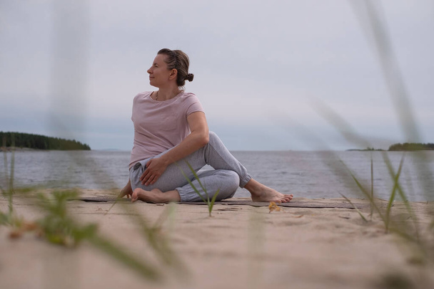 Donna che pratica yoga sulla spiaggia di sabbia. - Foto, immagini
