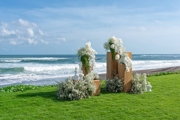 Hochzeitsvorbereitung, ein Hochzeitsbogen am Meer, geschmückt mit weißer Blume - Foto, Bild