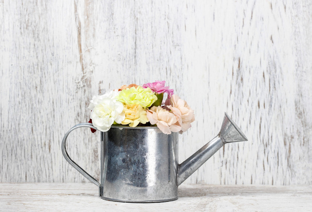 Beautiful carnation flowers in silver watering can, on wood - 写真・画像