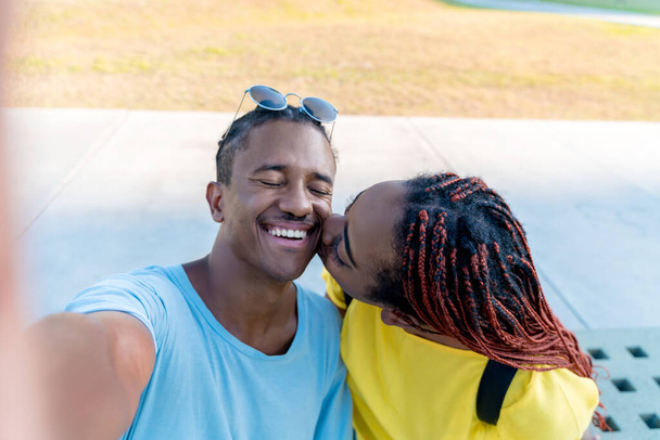Selfie of a kissing young black couple - 写真・画像