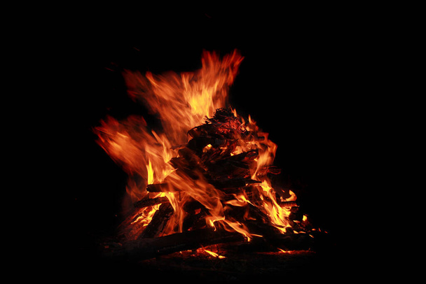 Bonfire at night. Around the total darkness In the outlines of burning heads you can see the head of the demon. Abstraction. imagination, mysticism - Foto, Imagen