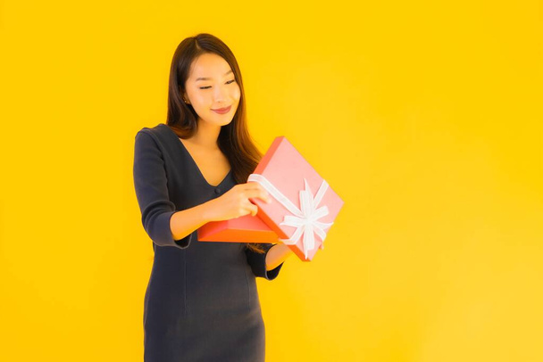 Portré gyönyörű fiatal ázsiai nő giftbox sárga elszigetelt háttér - Fotó, kép