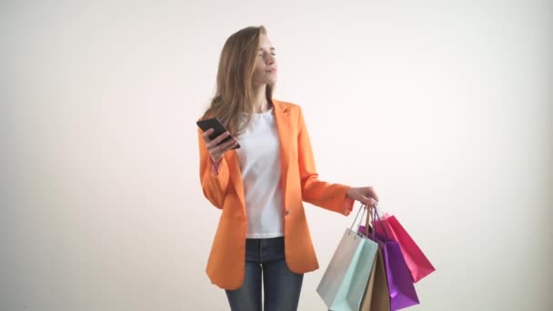 Beautiful young girl is shopping online with a phone in her hands. - Séquence, vidéo