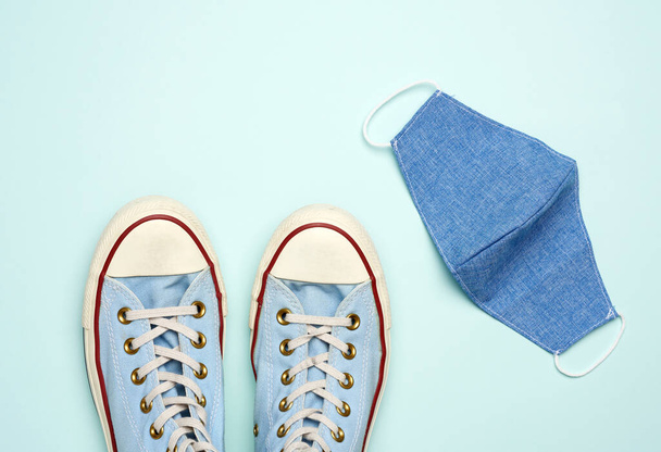 máscara textil reutilizable y zapatillas azules sobre un fondo azul, caminatas seguras durante una pandemia viral, vista superior, acostado plano
 - Foto, imagen