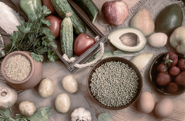 Μια ποικιλία βιολογικών τροφίμων στο ξύλινο τραπέζι: φρούτα, λαχανικά, αυγά, δημητριακά πλιγούρι, φασόλια με λαχανάκια. Η έννοια της υγιεινής διατροφής. Η θέα από την κορυφή - Φωτογραφία, εικόνα