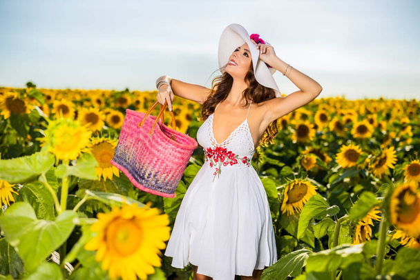Gyönyörű nő pózol a mezőgazdasági területen napraforgóval egy napos nyári napon - Fotó, kép